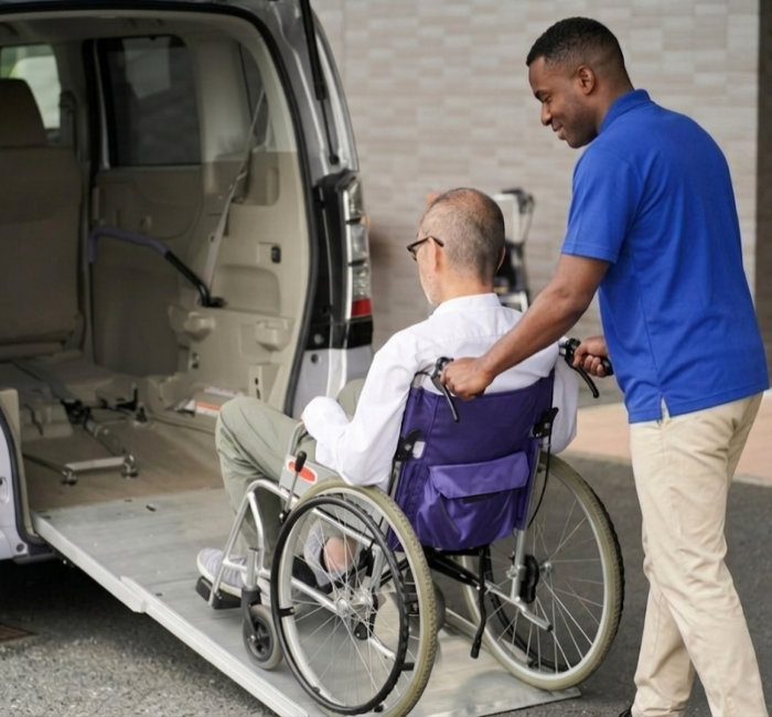 A man in a wheelchair is being pushed by another man also in a wheelchair, showcasing mobility and support. 